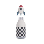 A white insulated bottle with a black and white checkerboard pattern near the bottom, topped with a detachable rocket-shaped lid featuring a red nose cone, gray fins, and a gray circular window.