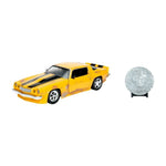 A yellow die-cast model car with black racing stripes and flame decals, shown alongside a silver commemorative coin on a small black stand against a plain white background.