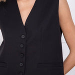 Model wearing KIDDING black tailored suiting vest as a standalone top with matching trousers, gold necklace, and sunglasses