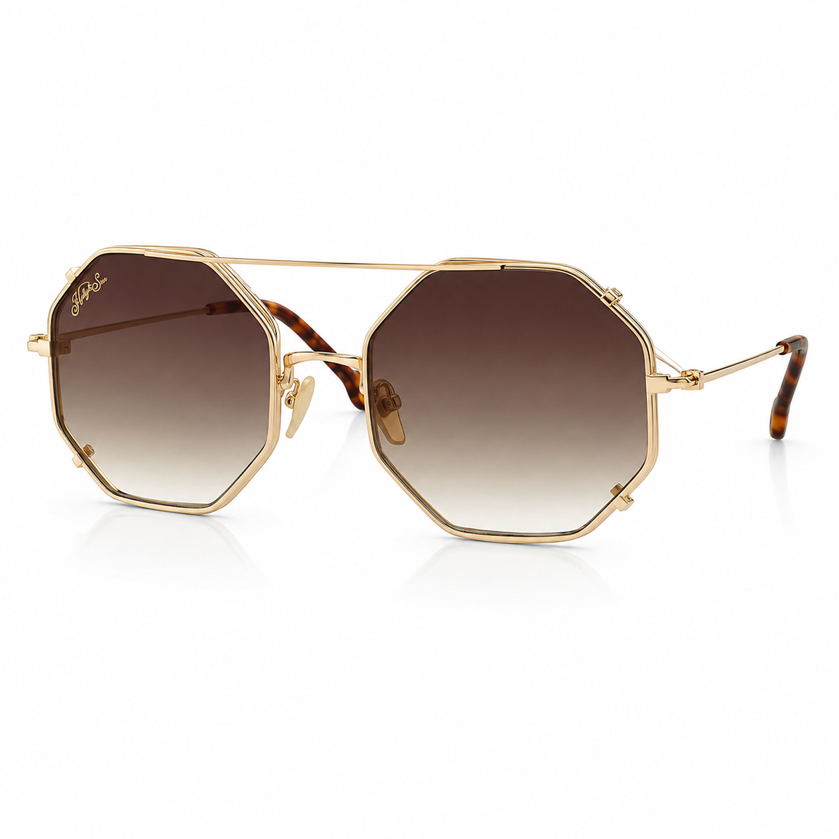 Hexagonal gold-framed sunglasses with gradient brown lenses and tortoiseshell temple arms, shown on a clean white background.