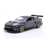 A dark gray die-cast model of a Ford Mustang with a widebody kit, gold multi-spoke wheels, and a rear spoiler, photographed on a white reflective studio background.