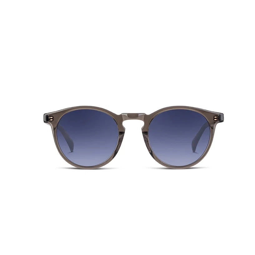 Round sunglasses with a translucent taupe-grey frame and dark blue gradient lenses, shown against a plain white background.