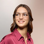 A woman wearing eyeglasses on a pink background. 