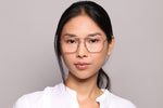 A woman wearing eyeglasses on a purple background. 