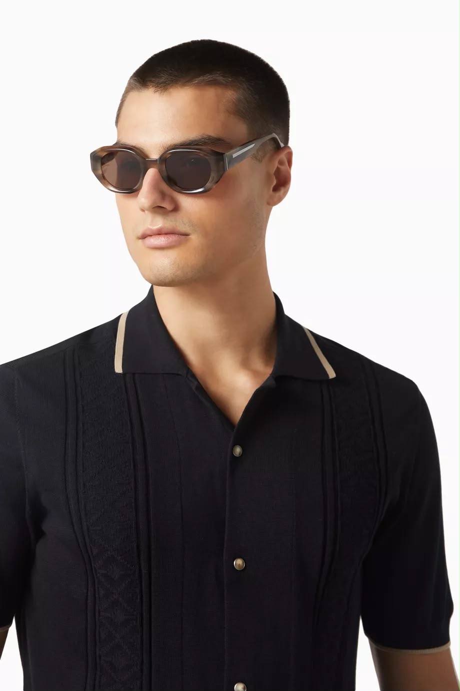 Side angle of a man wearing sunglasses with dark lenses on a white background. 