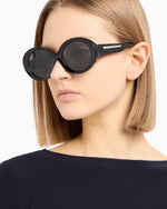 Side angle of a woman black sunglasses with dark tinted lenses n a white background. 