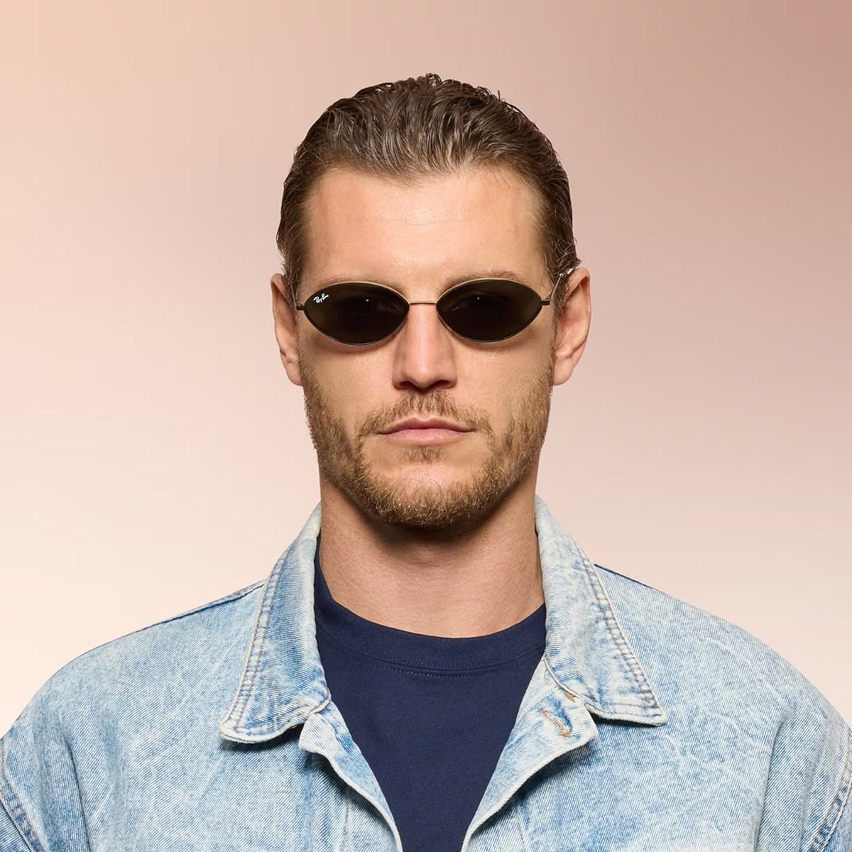 Front angle of a man wearing black sunglasses on a pink background. 