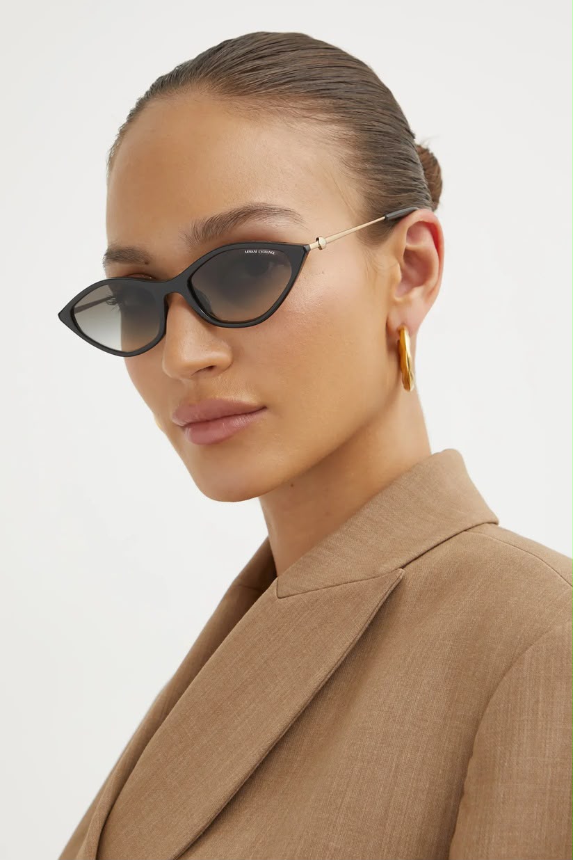 Side angle of a woman wearing black sunglasses with dark lenses on a white background. 
