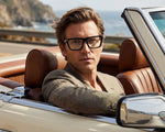 A man wearing black framed eyeglasses on a mountain-looking background. 