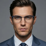 Front angle of a man wearing blue framed eyeglasses and a suit on a blue background. 