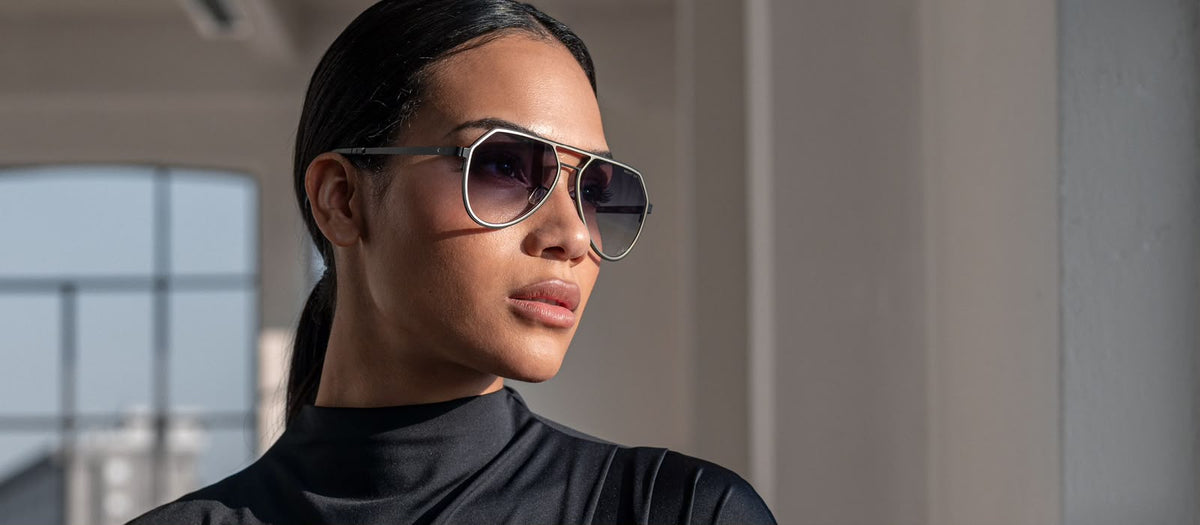 Side angle of a woman wearing black sunglasses with double bridge and dak lenses. 