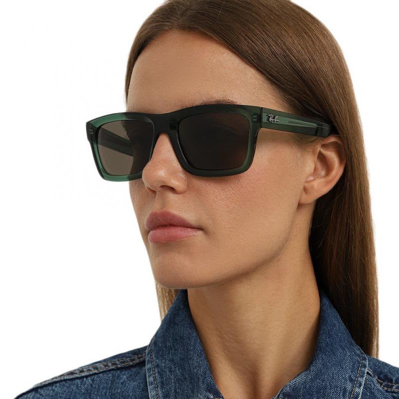 Side angle of a woman wearing dark green framed eyeglasses on a white background. 