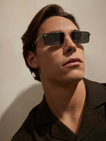 A man wearing silver framed sunglasses with dark lenses.