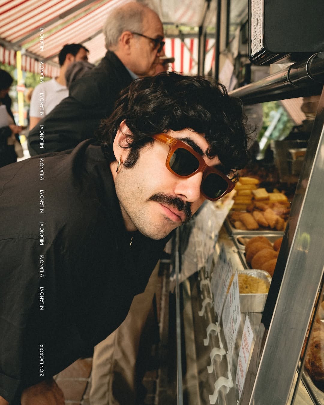 Side angle of a man wearing orange framed sunglasses iwth dark lenses.
