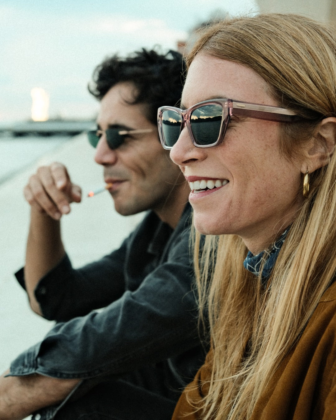 Side angle of a woman wearing pink framed sunglasses with dark lenses.