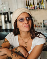A woman wearing sunglasses and a white beanie. 