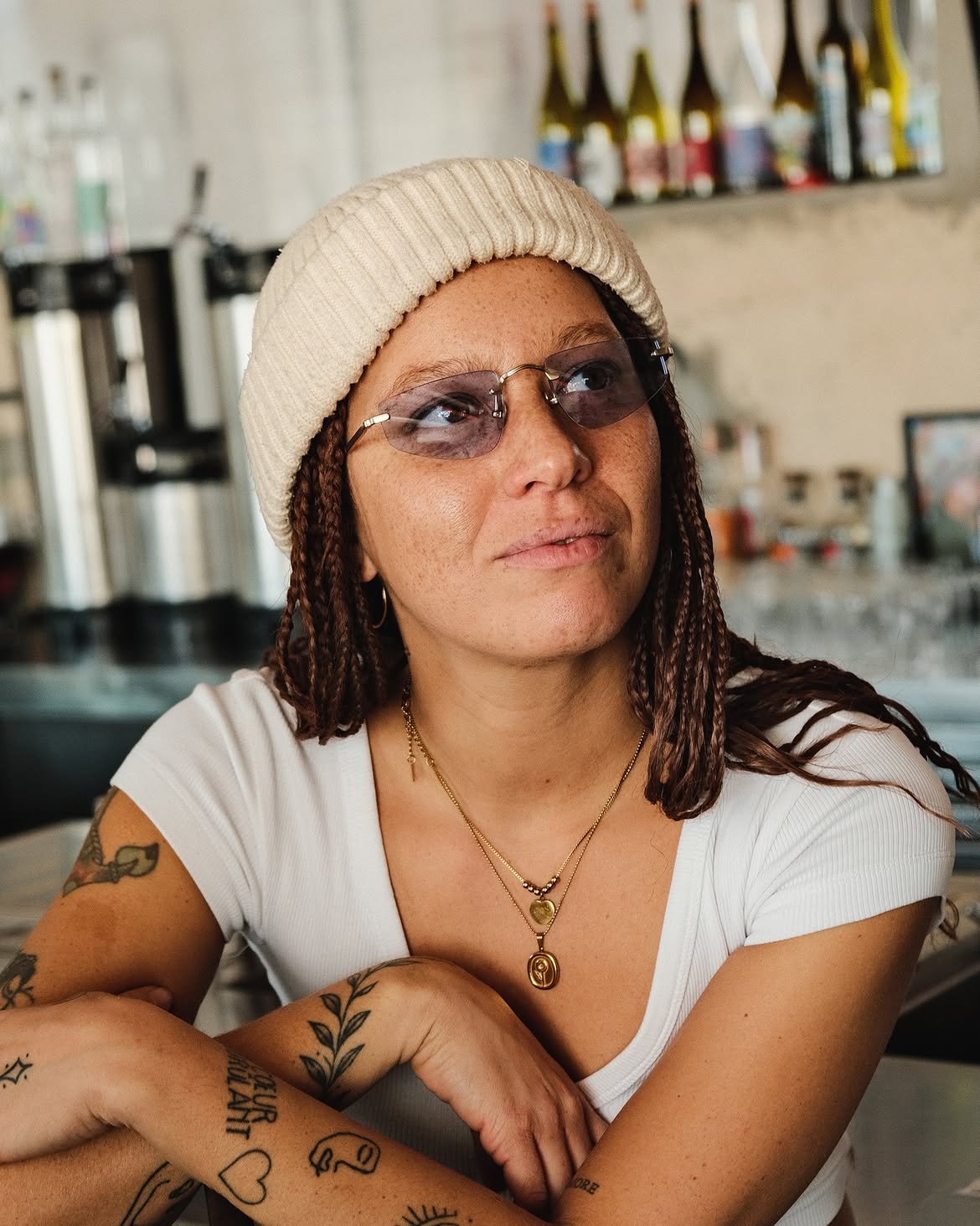 A woman wearing sunglasses and a white beanie. 